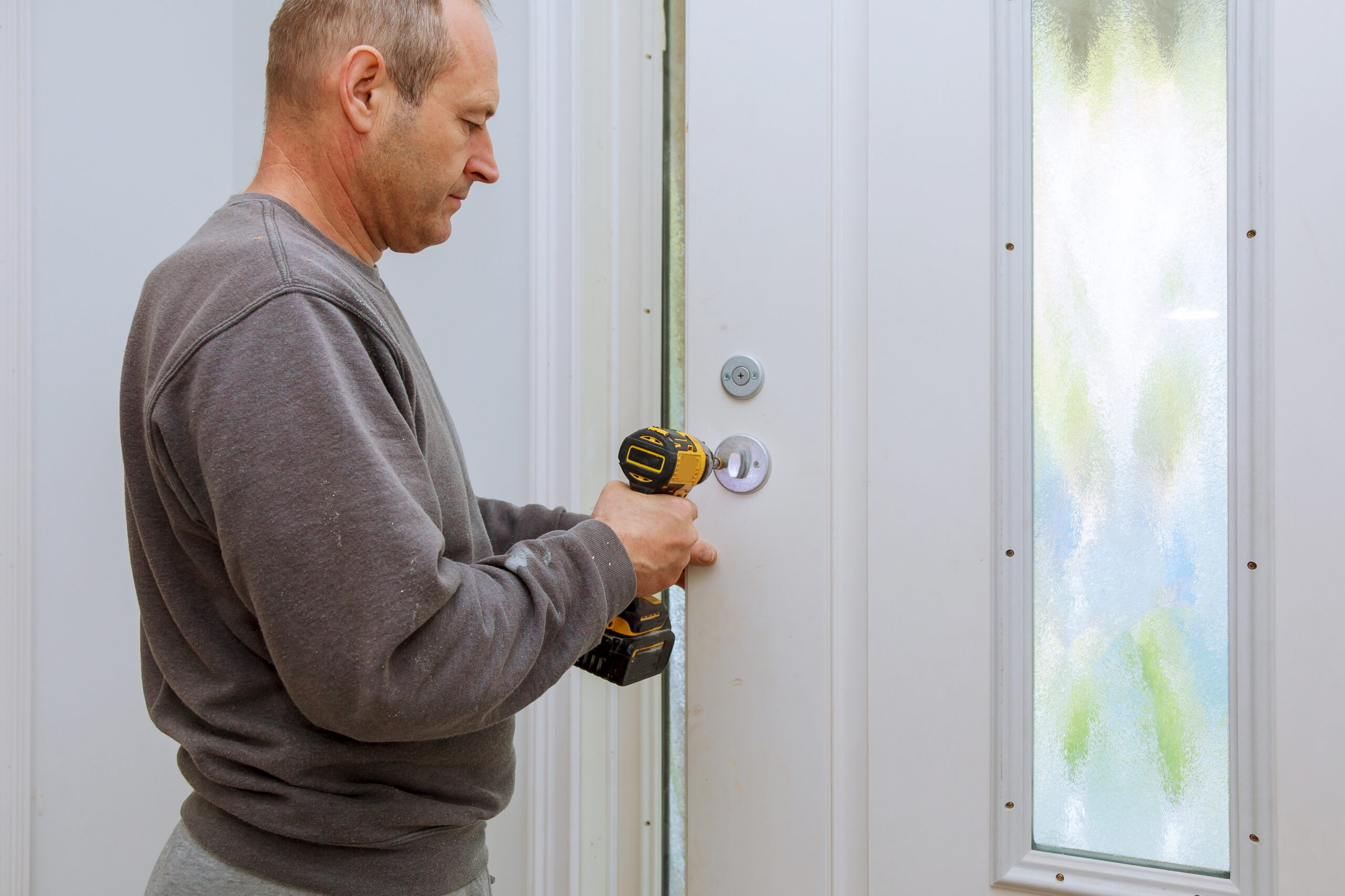 Installation locked interior door knobs, close-up wood worker hands install lock.